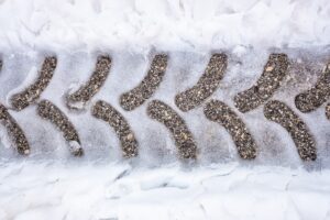 Traces of a tractor tire on snowy asphalt on a road in winter.