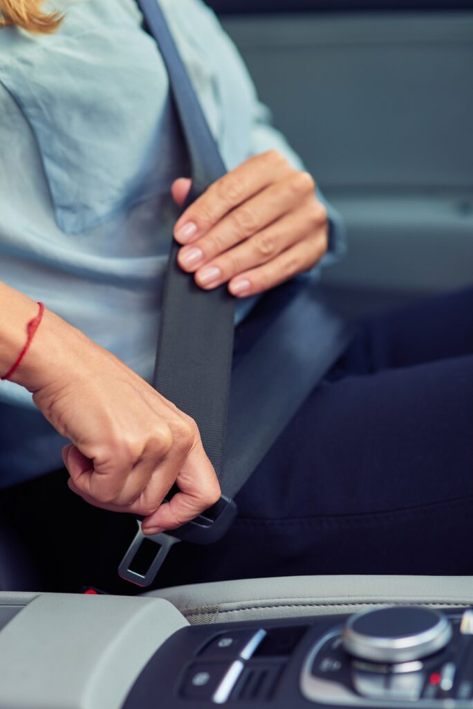 Driving safely. Cropped shot of a woman sitting behind steering wheel of her car and fastening seat